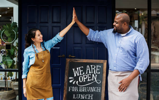 Cheerful business owners standing with open blackboard Cheerful business owners standing with open blackboard
